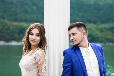 Couple standing by column against lake