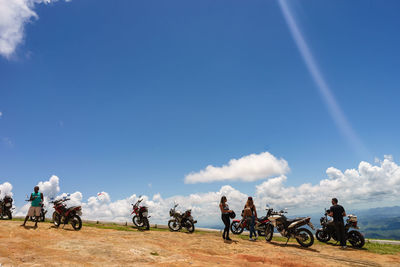 People riding bicycles on cart against sky