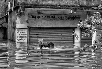 Portrait of young man in water against store during flood
