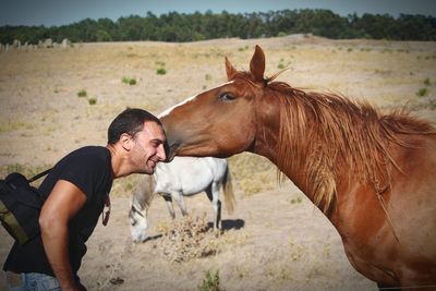 Horse kissing men while standing on field