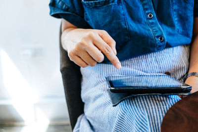 Midsection of woman using digital tablet