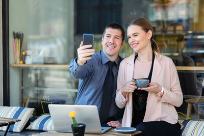 Young couple holding mobile phone at home