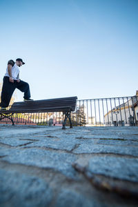 Surface level view of man standing on bench against sky