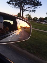 Car on side-view mirror against sky