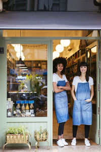 Portrait of two smiling women standing in entrance door of a store