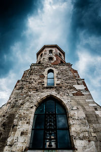 Low angle view of damaged bell tower against cloudy sky