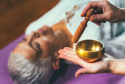 Cropped hands of woman playing singing bowl for customer in spa