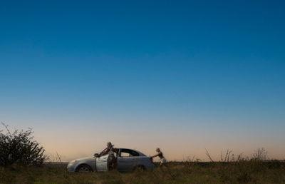 Car on field against clear blue sky