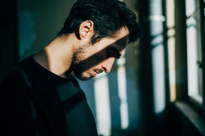 Close-up of young man by window