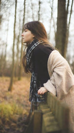 Side view of woman standing in forest