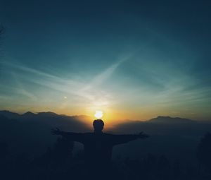 Rear view of silhouette man standing against sky during sunrise