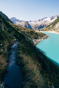 Scenic view of lake and mountains against clear blue sky