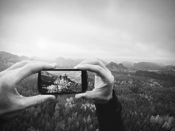 Man takes photos with phone on rock empire. dreamy foggy mountains, spring  misty sunrise in valley