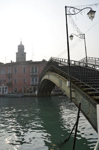 Bridge over river in city against sky