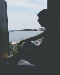 Side view of man sitting on boat against sea