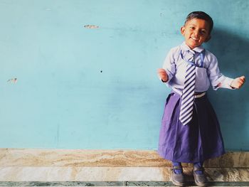 Portrait of smiling girl standing against wall with gesturing