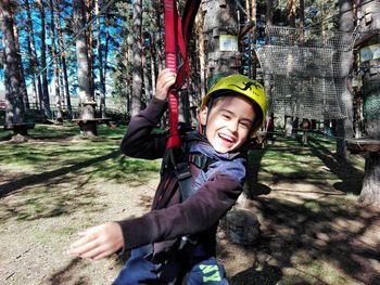 Portrait of smiling boy enjoying zip line in forest