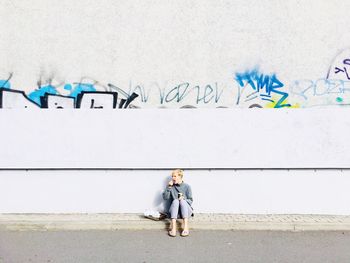 Full length portrait of woman standing against wall