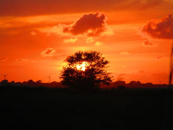 Silhouette trees on field against romantic sky at sunset