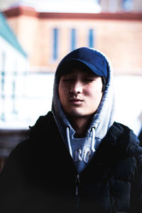 Young man wearing hooded jacket sitting with eyes closed