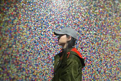Profile view of woman wearing cap against colorful wall
