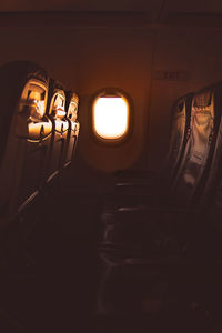 Airplane window against sky during sunset