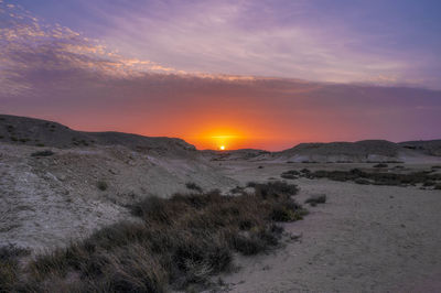 Scenic view of desert against sky during sunset