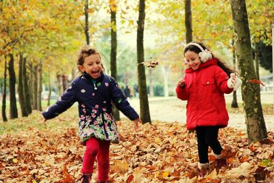 Siblings playing on field covered with dry leaves