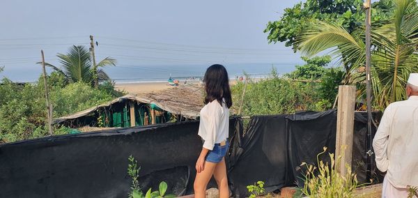 Rear view of woman walking on beach against sky