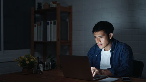 Young man using phone while sitting on table