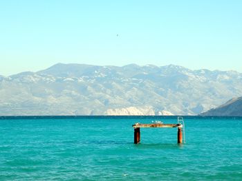 Scenic view of sea and mountains against clear blue sky