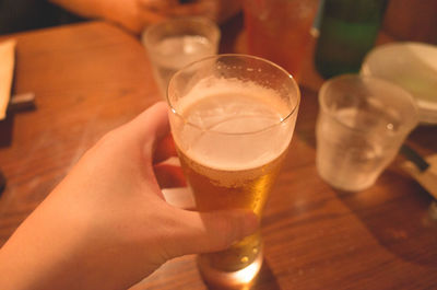 Close-up of hand holding beer glass on table