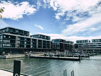 Buildings by river against sky in city