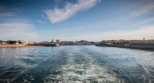 Scenic view of sea by buildings against sky