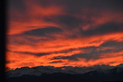 Scenic view of dramatic sky over silhouette mountains during sunset