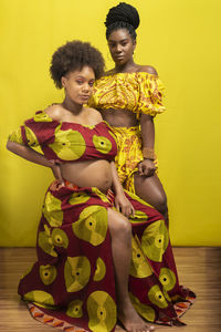 Portrait of two women against yellow background. motherhood and friendship concept.