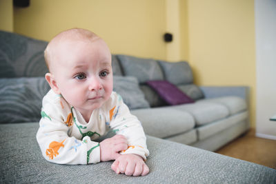 Portrait of cute baby boy sitting on sofa at home