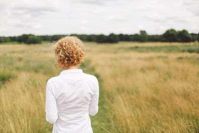 Rear view of blonde woman standing in field