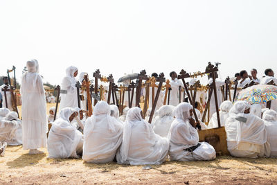 Group of people in row against clear sky