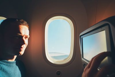 Smiling young man using technology while traveling in airplane