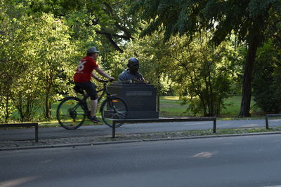 Rear view of man riding bicycle on road