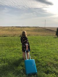 Rear view of woman on grassy field against sky