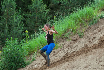 Side view of a young man running on dirt road