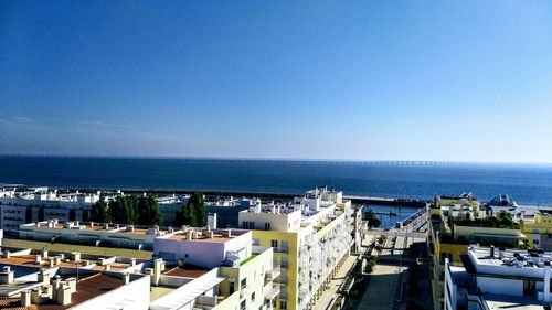 High angle view of buildings by sea against clear sky