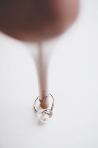 Low section of woman with stilettos and pearl ring on white background