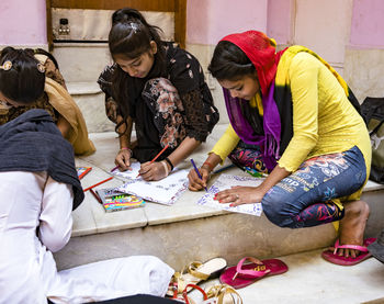 Rear view of two women sitting on floor