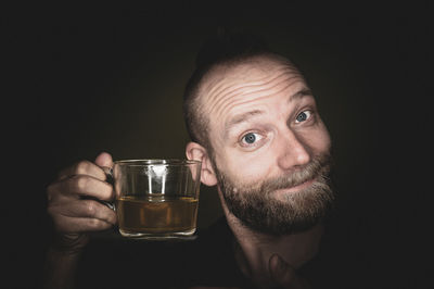 Portrait of man drinking glasses against black background