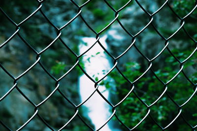 Close-up of chainlink fence against waterfall