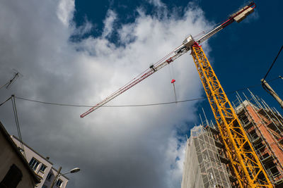 Low angle view of crane at construction site against sky