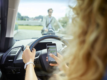 Young woman in electric car texting on cell phone